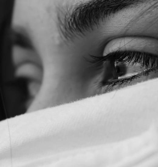 Close up shot of a person's eyes brimming with tears, rest of the face appears covered